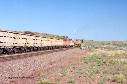 248-14
Dingo Siding on the Hamersley Iron railway at the 39 km with an empty train headed up by a pair of General Electric built Dash 9-44CW units 7077 serial 47756 from the original first order in the Pepsi Can livery and 9408 serial 54158 from the fourth order in the Pilbara Rail livery with Robe ownership markings powers away to the south back onto the mainline with the signal marker board DI19 for Dingo 19. Approximate [url=https://goo.gl/maps/Jv752bD5KXv28oUV7]location[/url]. 24th April 2004.
