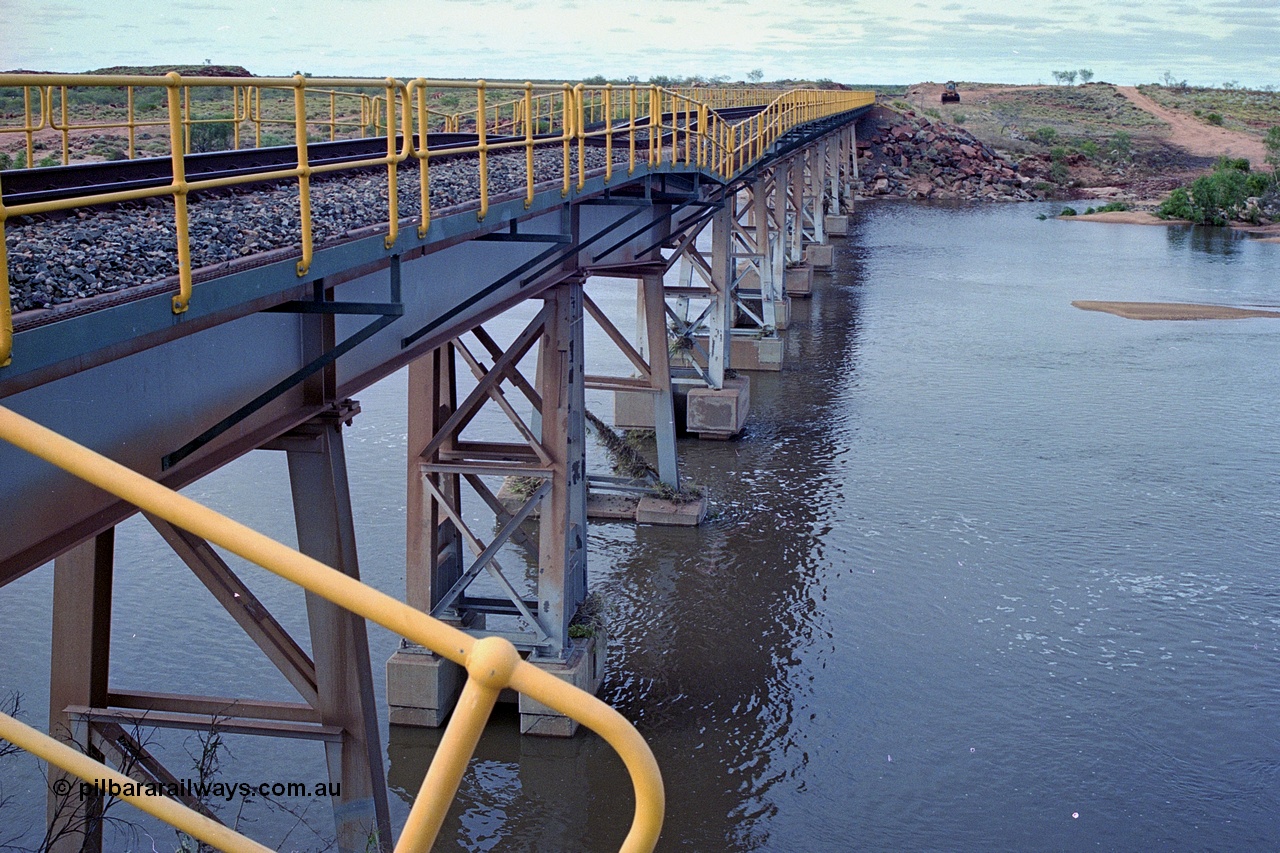 249-02
Yule River bridge looking north from the 160 km on the BHP mainline. The third pier from the southern end was undermined by flood waters from Tropical Cyclone John in December 1999. The rail line was closed for two weeks while repairs were effected. Approximate [url=https://goo.gl/maps/phCWr8u1xnuBdzwj6]location[/url].
