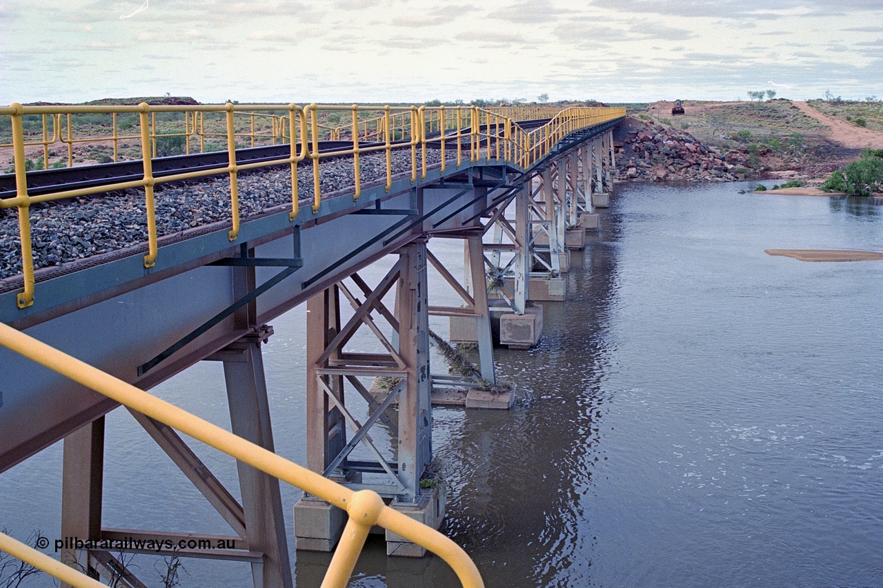 249-03
Yule River bridge looking north from the 160 km on the BHP mainline. The third pier from the southern end was undermined by flood waters from Tropical Cyclone John in December 1999. The rail line was closed for two weeks while repairs were effected. Approximate [url=https://goo.gl/maps/phCWr8u1xnuBdzwj6]location[/url].
