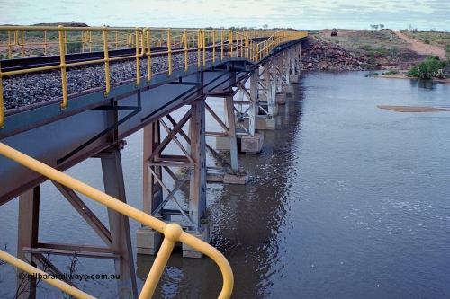 249-02
Yule River bridge looking north from the 160 km on the BHP mainline. The third pier from the southern end was undermined by flood waters from Tropical Cyclone John in December 1999. The rail line was closed for two weeks while repairs were effected. Approximate [url=https://goo.gl/maps/phCWr8u1xnuBdzwj6]location[/url].
