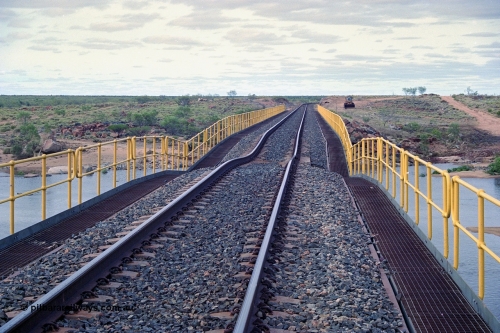 249-04
Yule River bridge looking north from the 160 km on the BHP mainline. The third pier from the southern end was undermined by flood waters from Tropical Cyclone John in December 1999. The rail line was closed for two weeks while repairs were effected. Approximate [url=https://goo.gl/maps/phCWr8u1xnuBdzwj6]location[/url].

