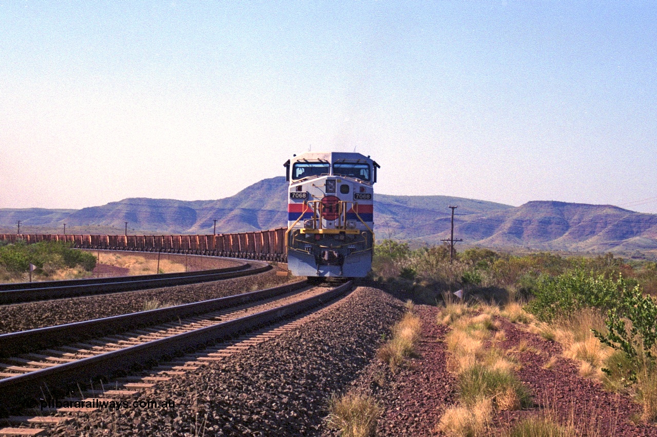 250-15
Pelican Siding on the Hamersley Iron Tom Price line about the 208 km with an empty train behind the standard pairing of two General Electric built 9-44CW units 7068 serial 47747 and 7067 serial 47746 stand on the loop or passing track for a meet with a loaded train. 1550 hrs 21st October 2000.
Keywords: 7068;GE;Dash-9-44CW;47747;