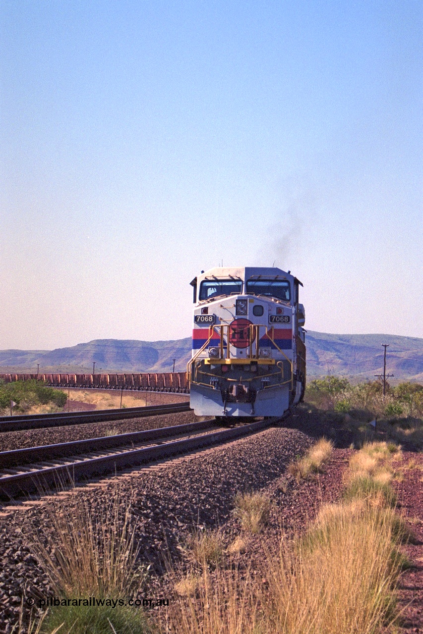 250-16
Pelican Siding on the Hamersley Iron Tom Price line about the 208 km with an empty train behind the standard pairing of two General Electric built 9-44CW units 7068 serial 47747 and 7067 serial 47746 stand on the loop or passing track for a meet with a loaded train. 1550 hrs 21st October 2000.
Keywords: 7068;GE;Dash-9-44CW;47747;