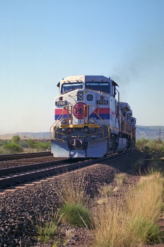 250-17
Pelican Siding on the Hamersley Iron Tom Price line about the 208 km with an empty train behind the standard pairing of two General Electric built 9-44CW units 7068 serial 47747 and 7067 serial 47746 stand on the loop or passing track for a meet with a loaded train. 1550 hrs 21st October 2000.
Keywords: 7068;GE;Dash-9-44CW;47747;