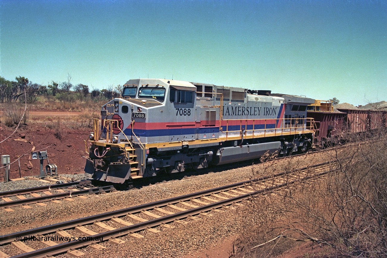 252-03
Cockatoo Siding 273 km on the Hamersley Iron line to Yandi, General Electric built 9-44CW unit 7088 with serial number 47767 from the original 1994 build idles away on the eastern end of the ballast train as it is loaded and slowly progresses into the back track siding Ballast plough BP 02 is behind the locomotive. Location is roughly [url=https://goo.gl/maps/bCvLZxMc1z57F8ym9]here[/url]. 24th November 2001.
Keywords: 7088;GE;Dash-9-44CW;47767;