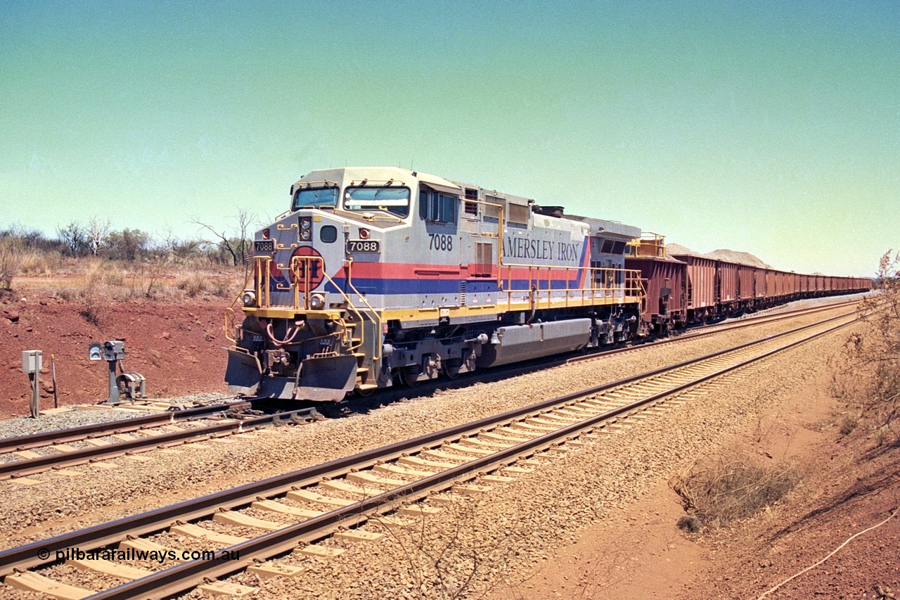 252-06
Cockatoo Siding 273 km on the Hamersley Iron line to Yandi, General Electric built 9-44CW unit 7088 with serial number 47767 from the original 1994 build idles away on the eastern end of the ballast train as it is loaded and slowly progresses into the back track siding Ballast plough BP 02 is behind the locomotive. Location is roughly [url=https://goo.gl/maps/bCvLZxMc1z57F8ym9]here[/url]. 24th November 2001.
Keywords: 7088;GE;Dash-9-44CW;47767;