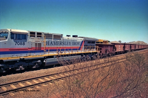252-09
Cockatoo Siding 273 km on the Hamersley Iron line to Yandi, General Electric built 9-44CW unit 7088 with serial number 47767 from the original 1994 build idles away on the eastern end of the ballast train as it is loaded and slowly progresses into the back track siding Ballast plough BP 02 is behind the locomotive. Location is roughly [url=https://goo.gl/maps/bCvLZxMc1z57F8ym9]here[/url]. 24th November 2001.
Keywords: 7088;GE;Dash-9-44CW;47767;
