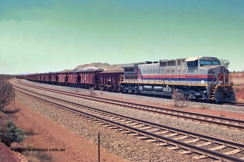 252-14
Cockatoo Siding 273 km on the Hamersley Iron line to Yandi, General Electric built 9-44CW unit 7087 with serial number 47766 from the original 1994 build idles away on the western end of the ballast train as it is loaded and slowly progresses into the back track siding Ballast plough BP 01 is behind the locomotive. Location is roughly [url=https://goo.gl/maps/rNdCHRcDhbQuHTjd7]here[/url]. 24th November 2001.
Keywords: 7087;GE;Dash-9-44CW;47766;