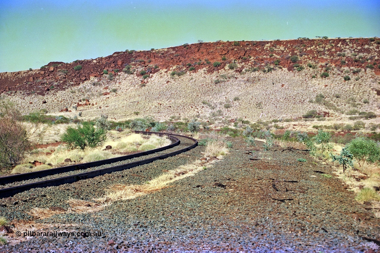 255-17
At the 162.2 km looking south are the remains of the second Robe River loadout facility which was installed in 1975 to mine the Mesa 2402E mining area, the line was a four kilometre U shaped spur curving away to the left. Geodata [url=https://goo.gl/maps/DATgFuHfuayyAp8y9]location here[/url]. May 2002.
