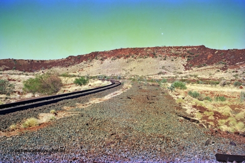 255-16
At the 162.2 km looking south are the remains of the second Robe River loadout facility which was installed in 1975 to mine the Mesa 2402E mining area, the line was a four kilometre U shaped spur curving away to the left. Geodata [url=https://goo.gl/maps/DATgFuHfuayyAp8y9]location here[/url]. May 2002.
