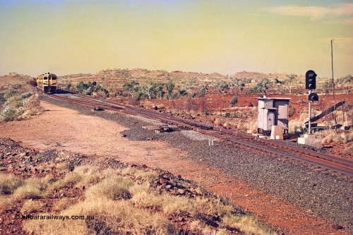 256-05
Maitland Siding located between the 92.8 and 95.1 km on the Cape Lambert line, view of the south end points and swing nose frog with dragging detector bars, solar panel and cabinets for signal and point control with an empty train sitting in the passing track awaiting a meet. May 2002.

