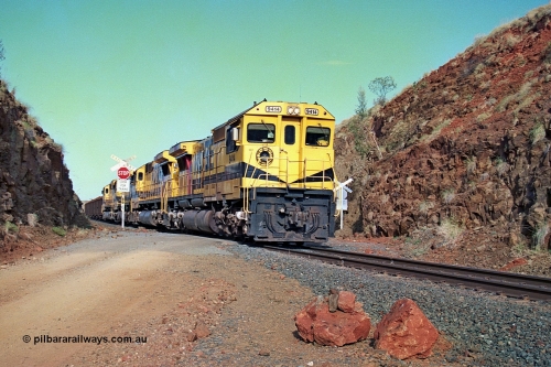 256-33
At the 89.6 km grade crossing the loaded train behind the quad CM40-8M working of 9414, 9420, 9410 and 9425 rolls across the crossing and heads down the 1.26 percent grade. 9414 was built by AE Goodwin NSW as an ALCo M636 model in December 1971 with serial number G-6060-5 and part of the original order for five units. Locomotive was delivered to Robe River in January 1972 with Bechtel Pacific road umber 262.005 for construction use and was renumbered 1714 when that was completed. 9414 was rebuilt by Goninan WA in November 1991 to become an CM40-8M model with serial number 8206-11 / 91-124. May 2002.
Keywords: 9414;Goninan;GE;CM40-8M;8206-11/91-124;rebuild;AE-Goodwin;ALCo;M636;G6060-5;