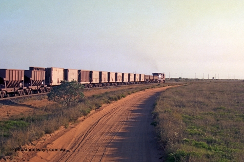 257-27
Goldsworthy Junction, an empty train runs between the junction and the Broome Rd crossing behind the standard single locomotive 5646 'White Springs', a Goninan 1992 built GE CM40-8 model with serial number 5244-11 / 92-135. The four styles of waggon in use are visible, behind the loco are three Golynx waggons, then a number of Gunderson USA builds, the ribbed type is a Portec USA built and then following are the Tomlinson WA and Scotts of Ipswich built 70 ton waggons. Late 2001.
