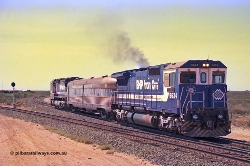 267-20
Goldsworthy Junction, CM40-8M GE unit 5634 'Boodarie' serial number 8151-07 / 91-120 leads the Sundowner Special on the Newman mainline leg of the Goldsworthy Junction and triangle, with the Sundowner coach in the middle and sister CM40-8M 5653 bringing up the rear.
This train, and the empty before it, were delayed due to a jamming switch for the transfer road where Tamper 2 and Ballast Regulator 31 are holding track. They can be seen behind the signal sitting on the transfer road. Friday 12th of April 2002.
Keywords: 5634;Goninan;GE;CM40-8M;8151-07/91-120;rebuild;AE-Goodwin;ALCo;C636;5457;G6027-1;
