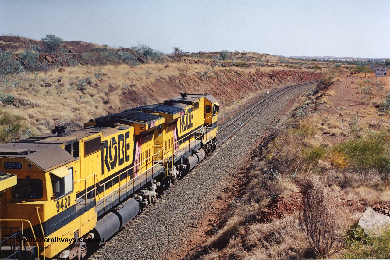 283-34
Near Woodbrook as quad Robe River CM40-8M units 9414, 9420, 9410 and 9525 work a loaded 202 waggons bound for Cape Lambert as they pass through the cutting at the 37.5 km pipe bridge. 9420 which is a Goninan WA ALCo to GE rebuild CM40-8M with serial 8109-03 / 91-119 from March 1991 riding on Hi-Ad bogies and was originally an ALCo Schenectady built C630 serial 3486-4 and built new for Chesapeake & Ohio (USA) as their 2103. It is one of four C630 ALCo units purchased in 1974 and delivered to Robe in January 1975. Everything below the frame is ALCo while above is GE and Pilbara Cab. 22nd May 2002.
Keywords: 9420;Goninan;GE;CM40-8M;8109-03/91-119;rebuild;ALCo;C630;3486-4;C+O;2103;