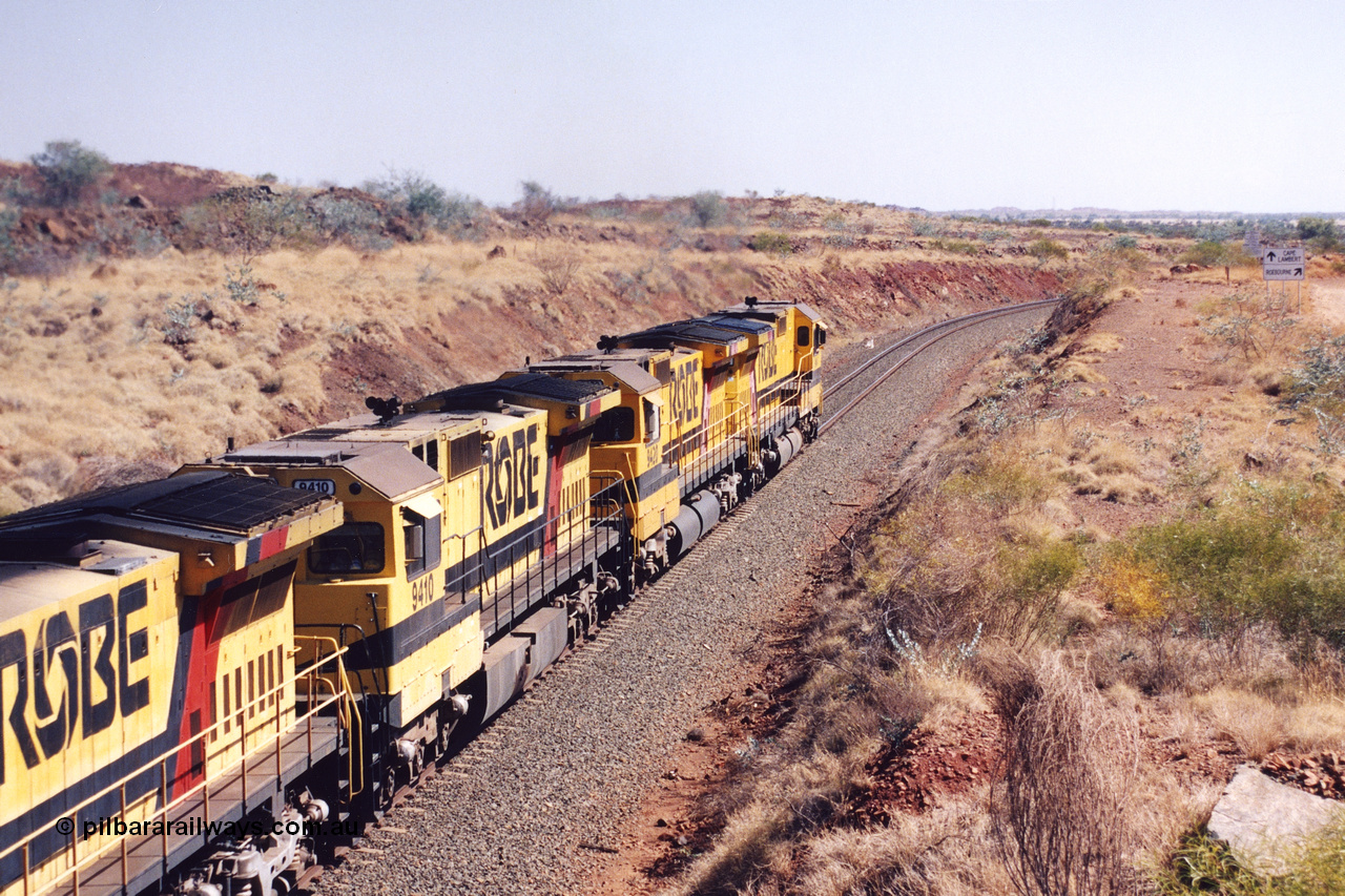 283-35
Near Woodbrook as quad Robe River CM40-8M units 9414, 9420, 9410 and 9525 work a loaded 202 waggons bound for Cape Lambert as they pass through the cutting at the 37.5 km pipe bridge. 9410 which is a Goninan WA ALCo to GE rebuild CM40-8M with serial 2160-03 / 96-202 from March 1996 riding on Dofasco bogies and was originally a Comeng NSW built M636 ALCo serial C-6096-5 and built new for Mt Newman Mining (later BHP Iron Ore) in November 1975 and numbered 5500. Everything below the frame is ALCo, with the Comeng build style flat fuel tank, while above is GE and Pilbara Cab. 22nd May 2002.
Keywords: 9410;Goninan;GE;CM40-8M;2160-03/96-202;rebuild;Comeng-NSW;ALCo;M636;C-6096-5;