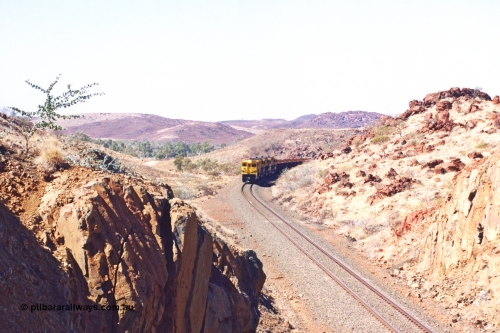 283-29
Near Woodbrook as the train rounds the curve just north of the 38.5 km grade crossing and through the cutting that will see it pass under the water pipe bridge behind the quad Robe River CM40-8M working of 9414, 9420, 9410 and 9525 with 202 waggons bound for Cape Lambert. 22nd of May 2002.
