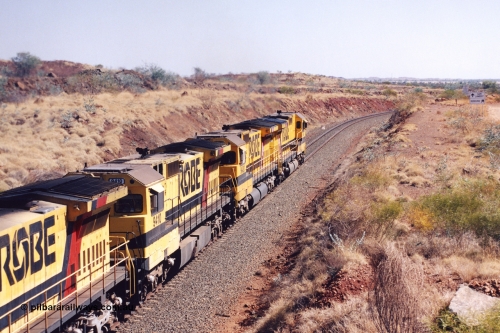283-35
Near Woodbrook as quad Robe River CM40-8M units 9414, 9420, 9410 and 9525 work a loaded 202 waggons bound for Cape Lambert as they pass through the cutting at the 37.5 km pipe bridge. 9410 which is a Goninan WA ALCo to GE rebuild CM40-8M with serial 2160-03 / 96-202 from March 1996 riding on Dofasco bogies and was originally a Comeng NSW built M636 ALCo serial C-6096-5 and built new for Mt Newman Mining (later BHP Iron Ore) in November 1975 and numbered 5500. Everything below the frame is ALCo, with the Comeng build style flat fuel tank, while above is GE and Pilbara Cab. 22nd May 2002.
Keywords: 9410;Goninan;GE;CM40-8M;2160-03/96-202;rebuild;Comeng-NSW;ALCo;M636;C-6096-5;