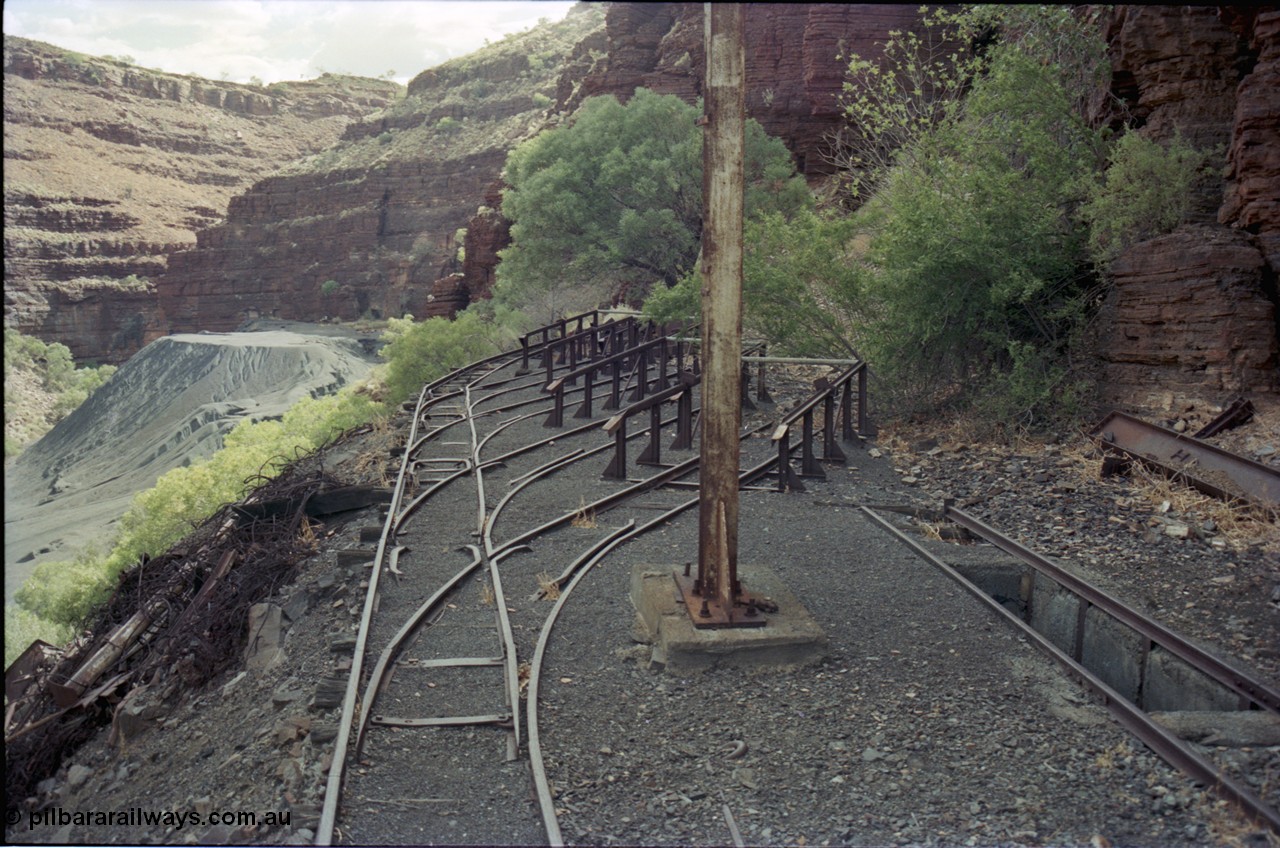 194-13
Wittenoom, Colonial Mine, asbestos mining remains, railway workshops with 4 loco storage roads and an inspection pit, the raised ramps are for removing the battery modules off the locomotives, looking south. Tailings in the background.
