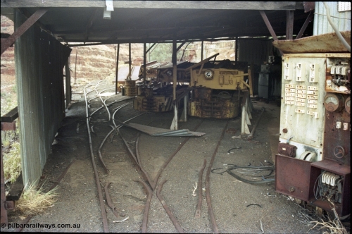 194-25
Wittenoom Gorge, Colonial Mine, asbestos mining remains, view into the loco workshop - battery charging shed, looking south, Mancha haulers with their battery modules on the racks, switchboard at right, with charging transformer visible in the background.
