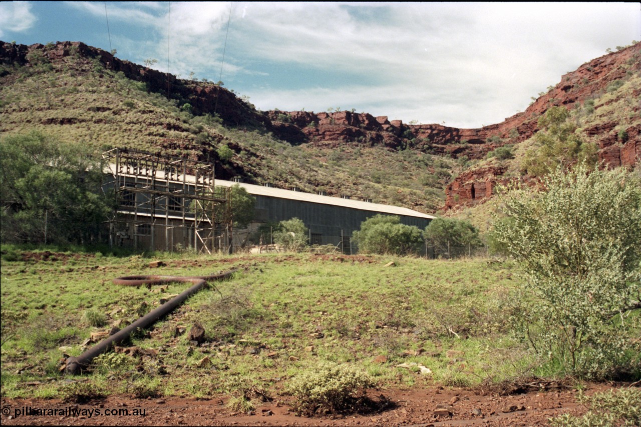 196-24
Wittenoom Gorge, view of power station generating hall with high voltage aerial conductors and the cooling water pipe visible.
