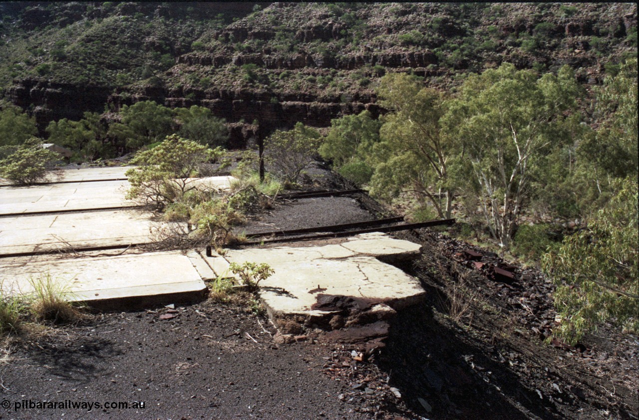 196-27
Wittenoom Gorge, Gorge Mine area, asbestos mining remains, view of demolished building with railway tracks in concrete floor, possible locomotive shop.
