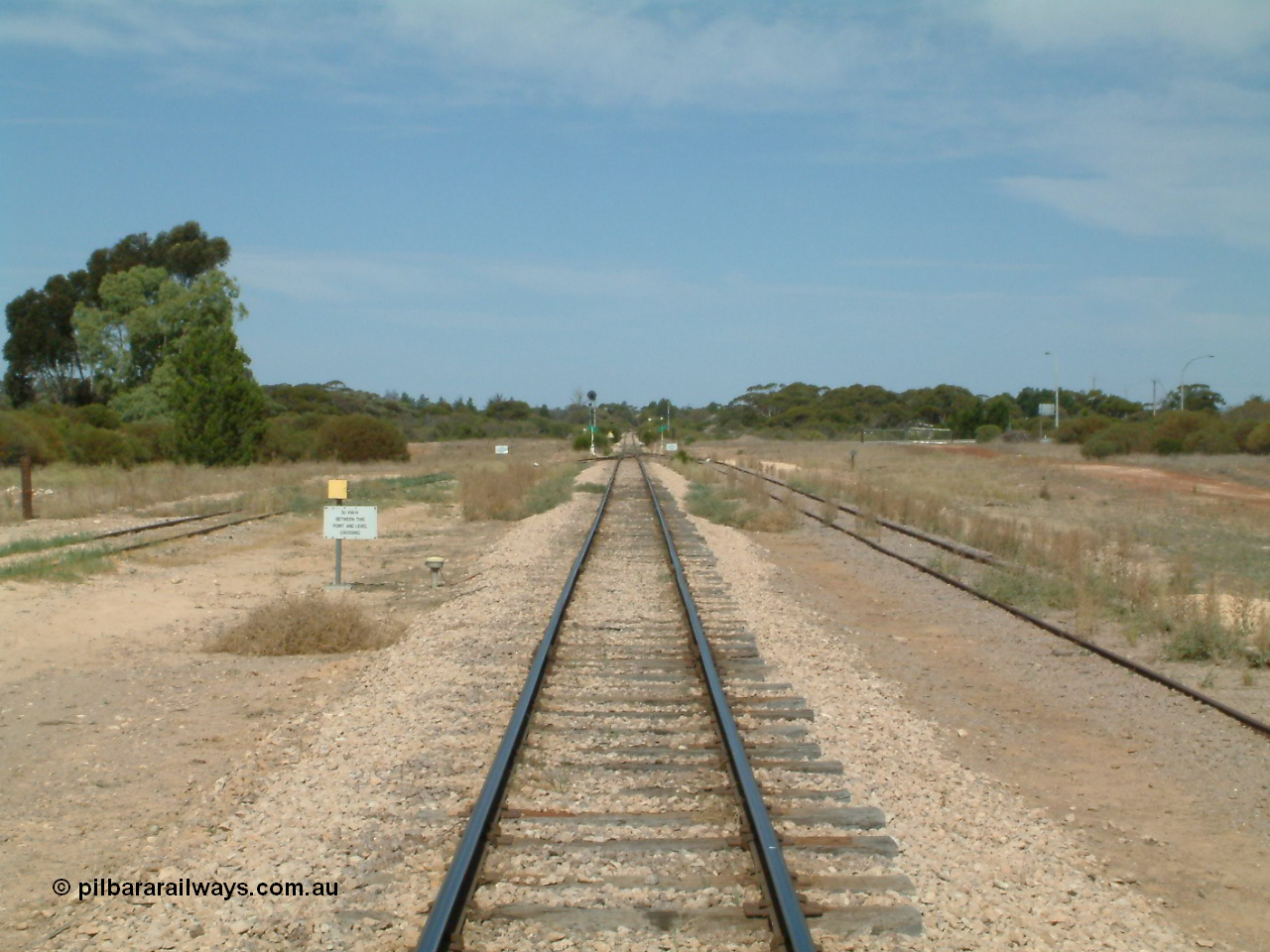 030405 140050
Kyancutta, yard view looking south along the narrow gauge mainline with the Eyre Highway grade crossing in the distance and one of only two electrically lit signals on the Eyre Peninsula Division. 5th April 2003.
