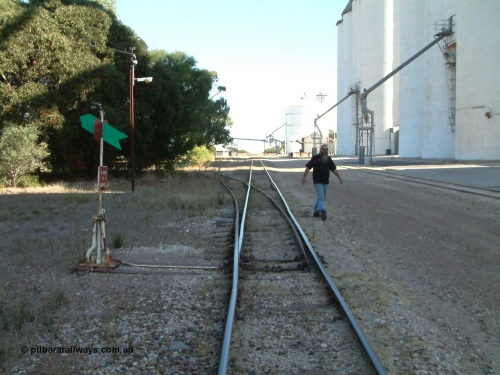 030405 155300
Lock, yard overview looking south, points and lever with indicator for the siding off the mainline, concrete silo complex Block 2 and outflow spout visible on the right as local identity Pope Searle wanders around the yard. April 5, 2003.
