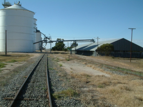 030405 155752
Lock, yard overview looking north along the grain siding, mainline to the right, Ascom style silo complex Block 5 with outflow spout visible on the left, point lever and indicator for horizontal grain shed siding in the middle of frame, and transfer auger across tracks. April 5, 2003.

