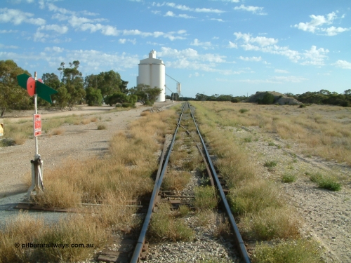 030406 084715
Tooligie, station yard overview looking north from the south end points, point lever and indicator, silo complex and outflow spouts on the left, old ballast pile on the right, former siding to the right of the mainline can still be made out for ballast loading site, 6th April 2003.
