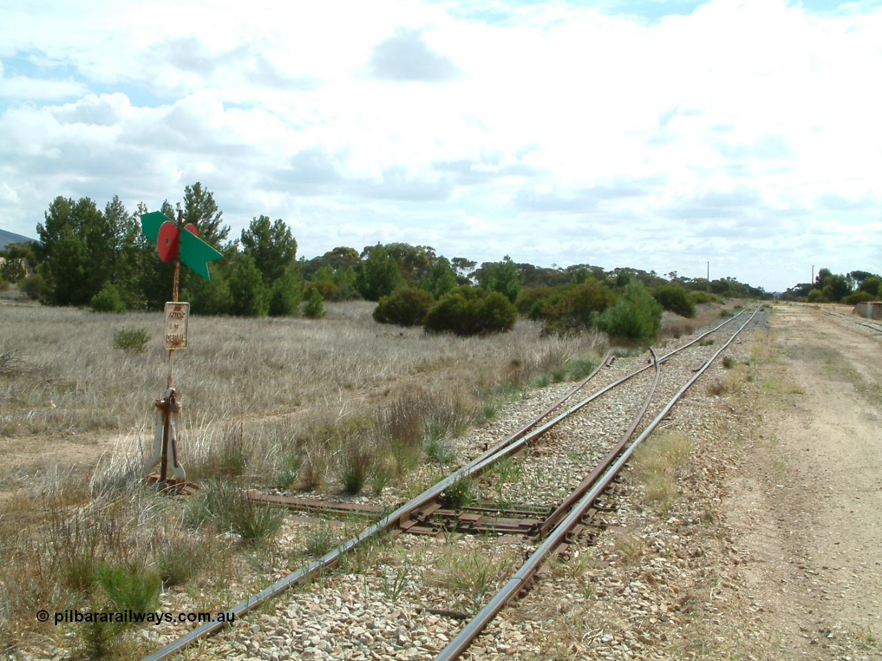 030409 112332
Darke Peake, view looking north from the south end of the triangle, point lever with rail just visible heading into the bush, goods and grain siding with loading ramp at far right.
