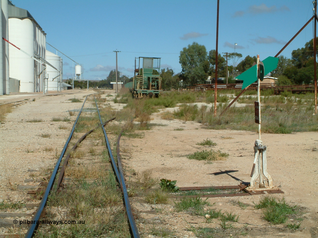 030411 105828
Kimba, station yard, view of rail transport set in the loading road, winch waggon, dumbbell point indicator. Barracks visible behind indicator, station building in the distance.

