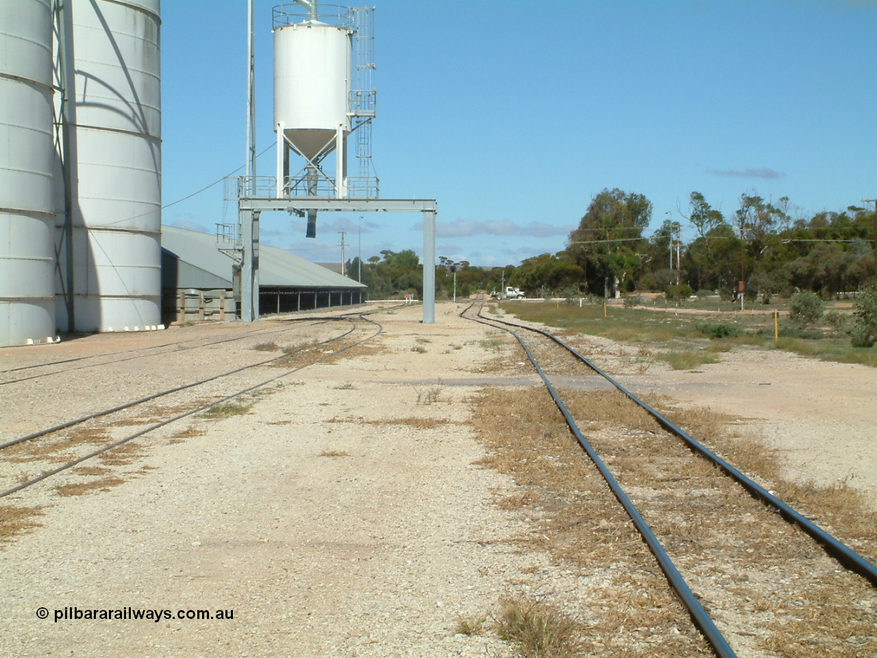 030411 110554
Kimba, yard view looking south, mainline on the right, Ascom loadout gantry and silo with horizontal bunker beyond that. Eyre Highway grade crossing in the distance.
