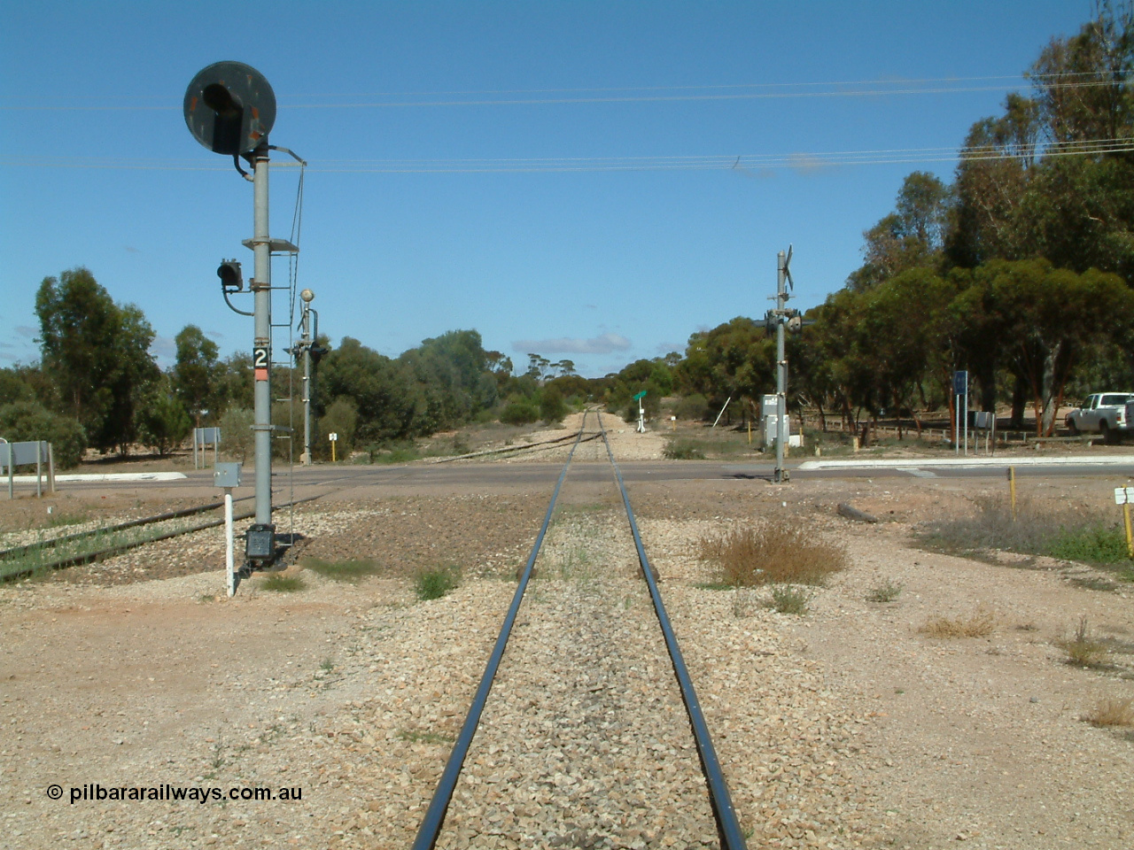030411 110823
Kimba, looking south across the Eyre Highway grade crossing, the mainline has a coloured light signal, one of only three such signals on the Eyre Peninsula system, the others being at Kyancutta and Port Lincoln.
