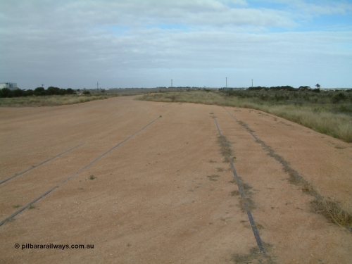 030414 154037
Penong, view looking east beside concrete silo block 2, grain loop on the left with mainline in centre of image and good loop in the grass on the right. Last train was March 1997.
