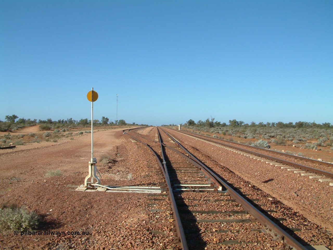 030416 084242
Carnes Siding located at the 566.4 km on the Central Australian line from Tarcoola to Alice Springs. View looking south from the north end of the goods siding rejoining the loop and the mainline at right. The train control 'pillbox' concrete hut is visible with the station nameboard the white item beside it. [url=https://goo.gl/maps/QbycvbbHxJHLg8h87]GeoData location[/url]. 16th April 2003.
