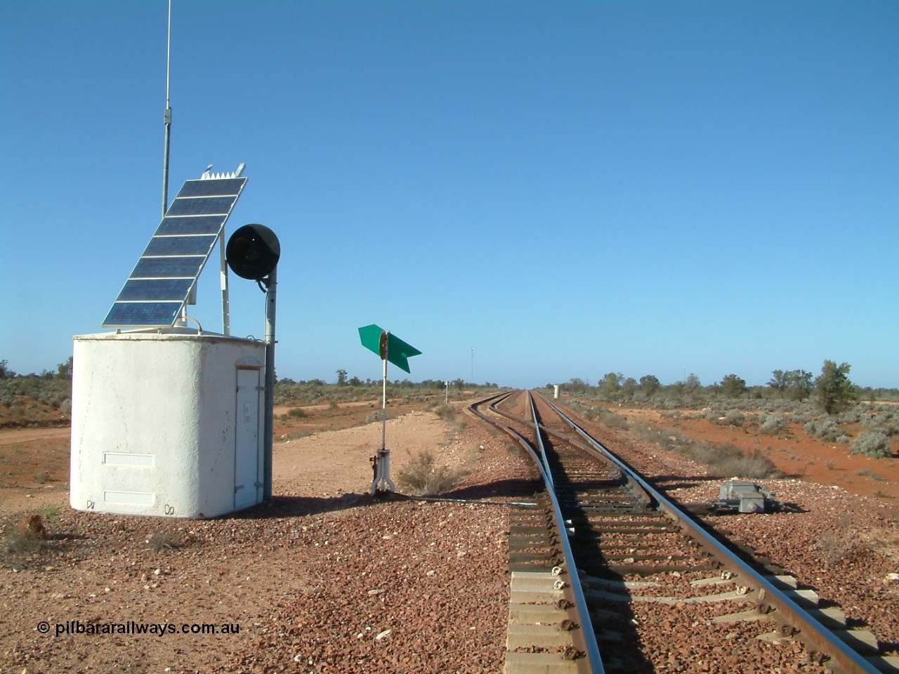 030416 084506
Carnes Siding located at the 566.4 km on the Central Australian line from Tarcoola to Alice Springs. Looking south from the north end of the loop, interlocking hut with repeater searchlight signal, point indicator and dual control point machine, in the distance the north end train control 'pillbox' can be seen. [url=https://goo.gl/maps/UV5pRwSrTaW3bxA76]GeoData location[/url]. 16th April 2003.
