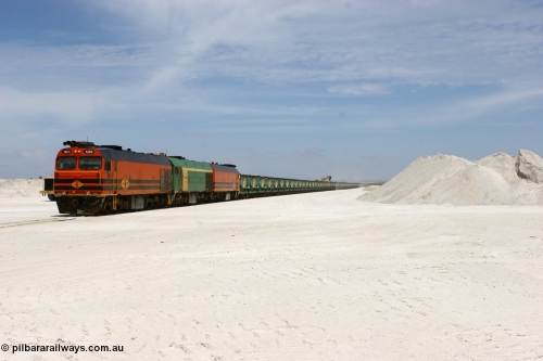 060113 2553
Kevin, standing on the mainline to Thevenard, and the train now identified as 6DD4 has commenced loading of gypsum but the 988 Cat front end loaders which takes about one and half hours to load. As the train reversed on the triangle the consist is the same heading back loaded with 1604 leading NJ 3 and 1601. 13th January 2006.
