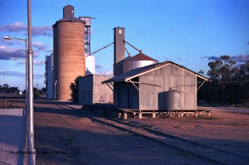 102-07
Woomelang yard view, station platform edge, goods shed and super phosphate shed, Geelong style and new and old style Ascom silo complexes, taken from down platform.
