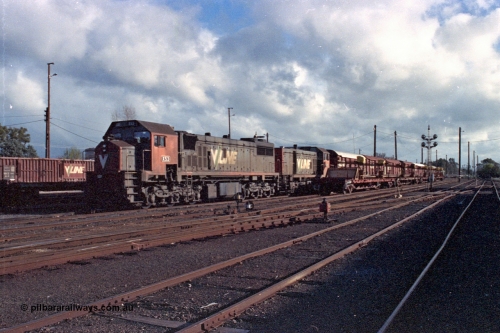 103-27
Benalla station yard overview, V/Line broad gauge stabled down Wodonga goods train 9303, locomotives V/Line X class loco X 53 with serial 75-800 a Clyde Engineering Rosewater SA built EMD model G26C and T class T 403 Clyde Engineering EMD model G18B serial 67-498, rail recovery rake beside stabled train, ground dwarf and disc signal posts, yard still intact.
Keywords: X-class;X53;Clyde-Engineering-Rosewater-SA;EMD;G26C;75-800;