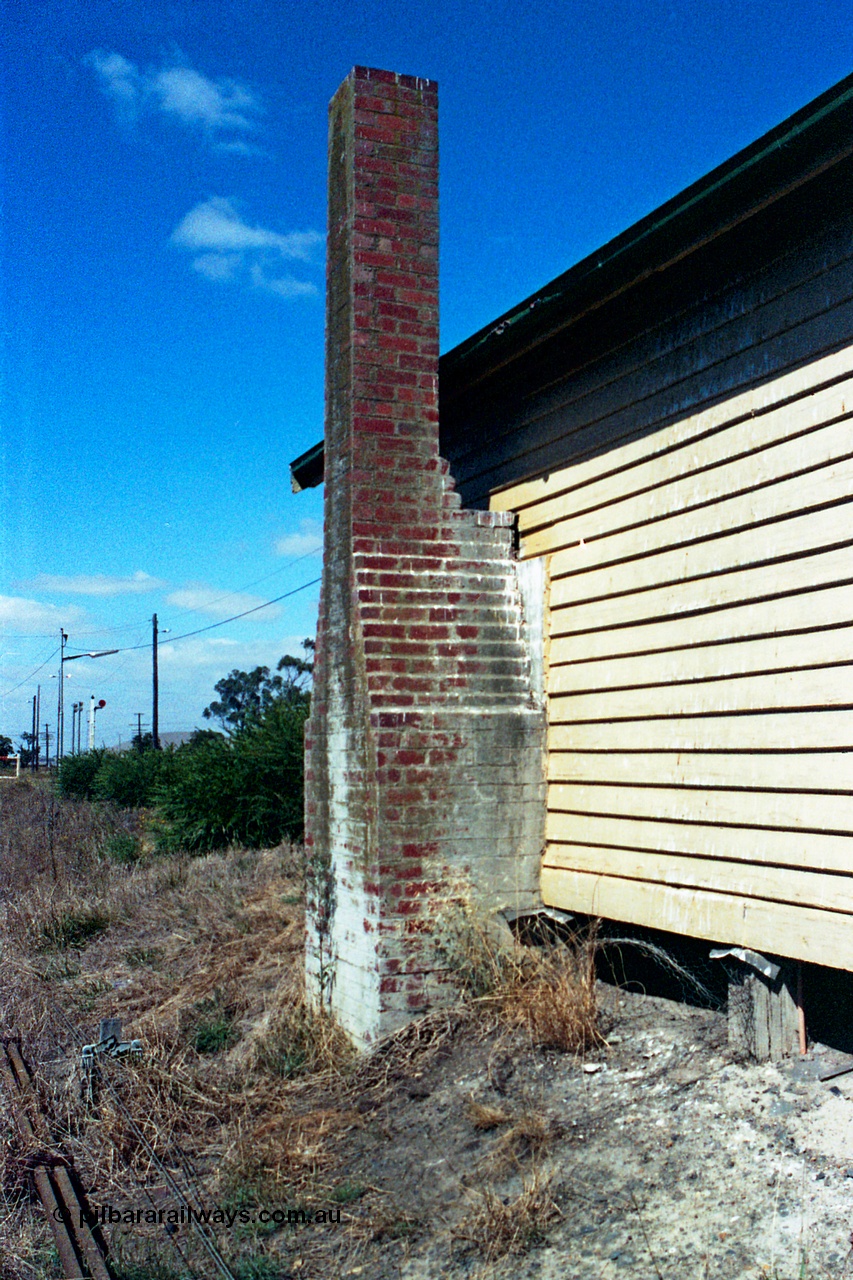 105-16
Wallan, station platform 2 waiting room, brick chimney, rear side elevation, point rodding and signal wires in grass view.
