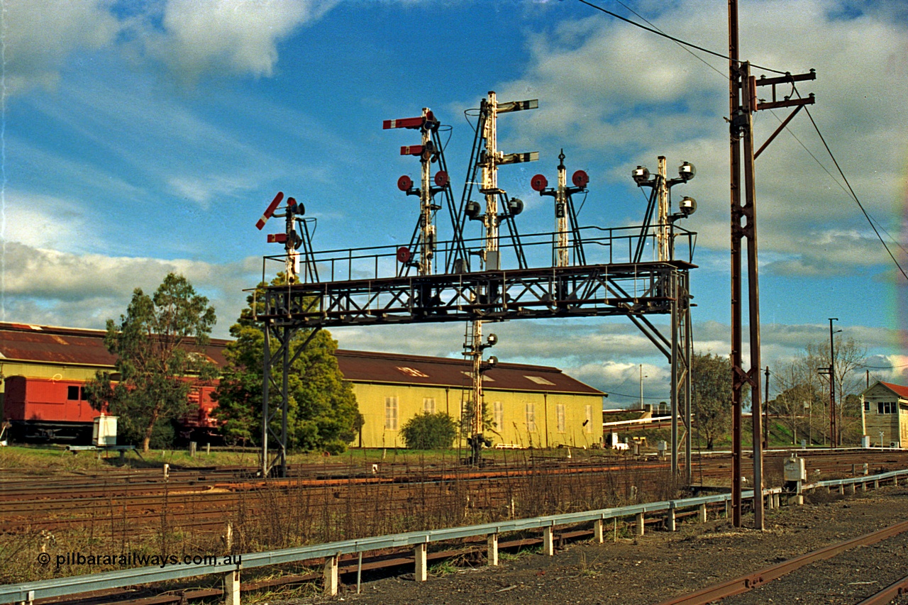 110-12
Benalla, the impressive signal gantry still intact in this view from 14th July 1991, only a couple of weeks later it was partially stripped of discs and semaphores, semaphore signal post 28 is pulled off for an up Albury passenger train, workshops behind and B signal box just visible on the right.
