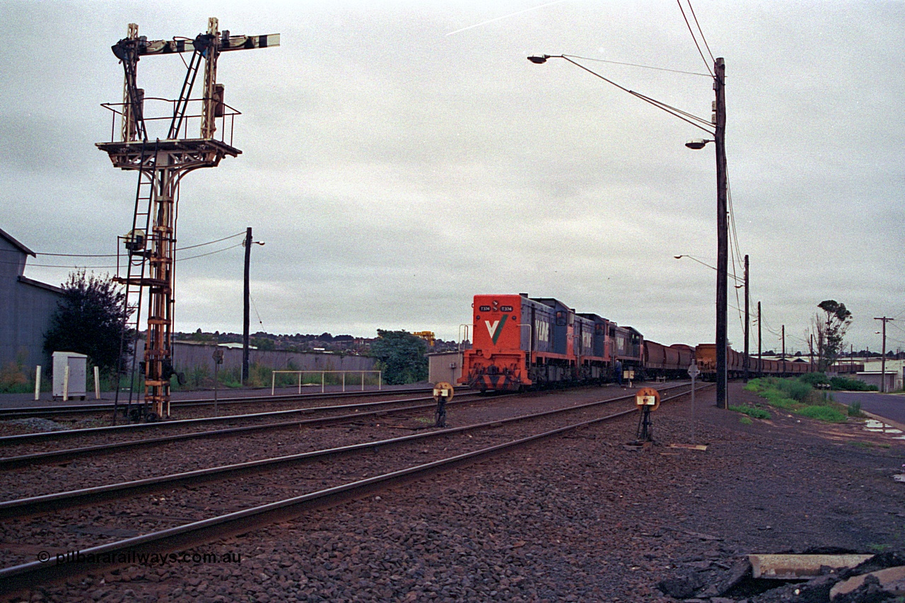 111-05
North Geelong grain arrivals yard, V/Line broad gauge locos T class T 374 Clyde Engineering EMD model G8B serial 64-329, T class 3?? and X class X 42 Clyde Engineering EMD model G26C serial 70-705 arrive with the up Mt Gambier goods train 9192, semaphore signal post 13 and ground dwarf disc signals 12 and 14 face away from the camera, loaded grain rake on the right.
Keywords: T-class;T374;Clyde-Engineering-Granville-NSW;EMD;G8B;64-329;