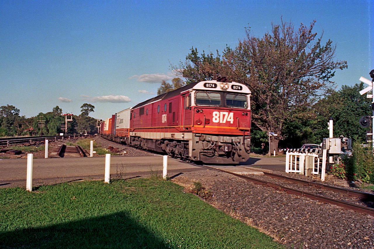 112-11
Violet Town, looking north across Cowslip Street, standard gauge NSWSRA 81 class 8174 Clyde Engineering EMD model JT26C-2SS serial 85-1093 in candy livery with an up goods heads south, station building behind camera, broad gauge track on the left, March 1994.
Keywords: 81-class;8174;Clyde-Engineering-Kelso-NSW;EMD;JT26C-2SS;85-1093;
