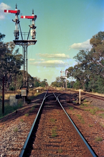 112-00
Violet Town broad gauge track view, looking north, down home semaphore signal post 2, road and signals cleared for up passenger train, calling on semaphores have been removed, standard gauge on the right, March 1994.
