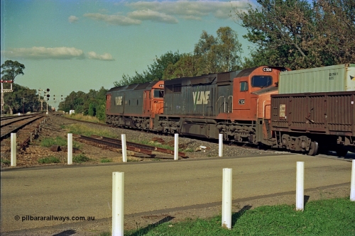 112-08
Violet Town, looking north across Cowslip Street, V/Line standard gauge down goods headed by G class G 529 Clyde Engineering EMD model JT26C-2SS serial 88-1259 and C class C 505 Clyde Engineering EMD model GT26C serial 76-828, trailing view, broad gauge lines at left, station building behind camera, 81 class on up goods holding the mainline in crossing loop in background, searchlight signals for standard gauge trains and semaphores for broad gauge, March 1994.
Keywords: G-class;G529;Clyde-Engineering-Somerton-Victoria;EMD;JT26C-2SS;88-1259;C-class;C505;GT26C;76-828;