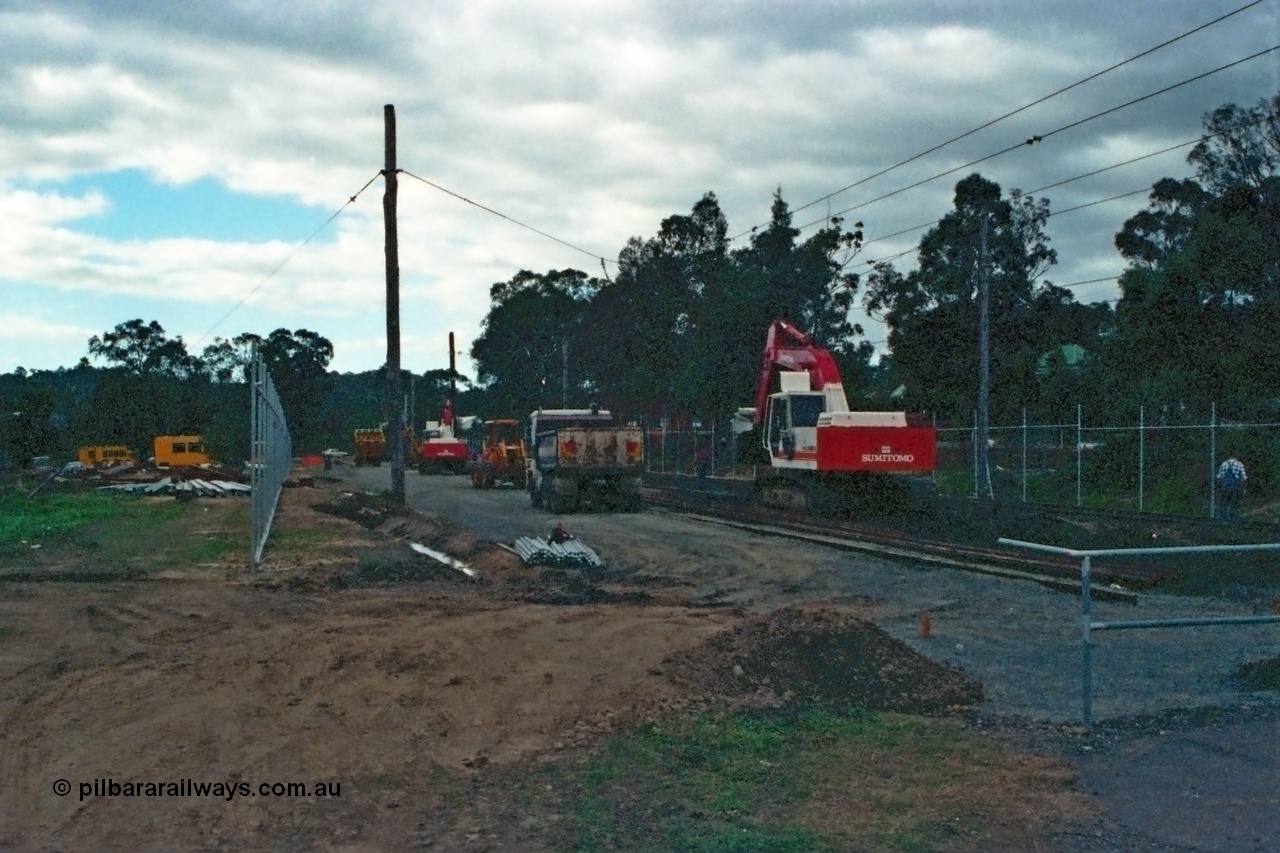 115-03
Hurstbridge, old stabling sidings being removed to make new stabling yard, new fencing, timber traction poles, crib crossing at right, Sumitomo excavator and workers.
