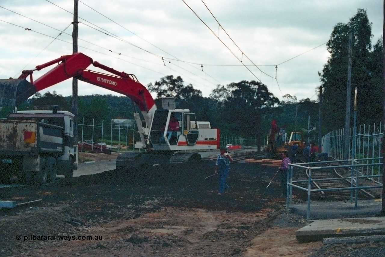 115-06
Hurstbridge, old stabling sidings being removed to make new stabling yard, new fencing, timber traction poles, crib crossing at right, Sumitomo excavator and workers.
