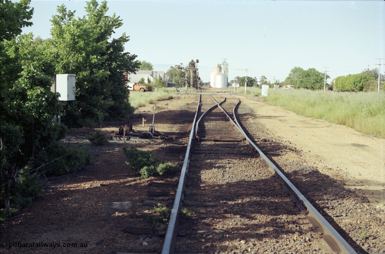 127-34
Elmore yard overview, looking towards Melbourne, points, point lever and interlocking facing up trains, near 207 km post, station building beyond grade crossing, silos in distance.
