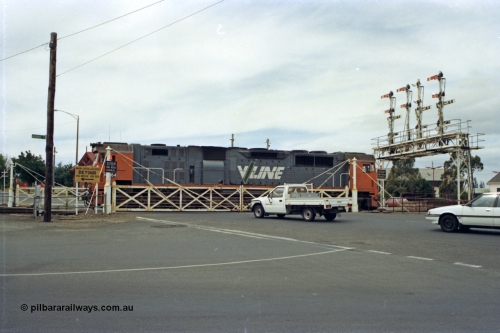128-15
Ballarat Station, Lydiard St or B signal box, view across Lydiard Street grade crossing with interlocked gates closed, signal gantry with semaphore signal posts 26 to 29, V/Line broad gauge N class N 464 'City of Geelong' Clyde Engineering EMD model JT22HC-2 serial 86-1193 shunts around train crossing Lydiard Street.
Keywords: N-class;N464;Clyde-Engineering-Somerton-Victoria;EMD;JT22HC-2;86-1193;